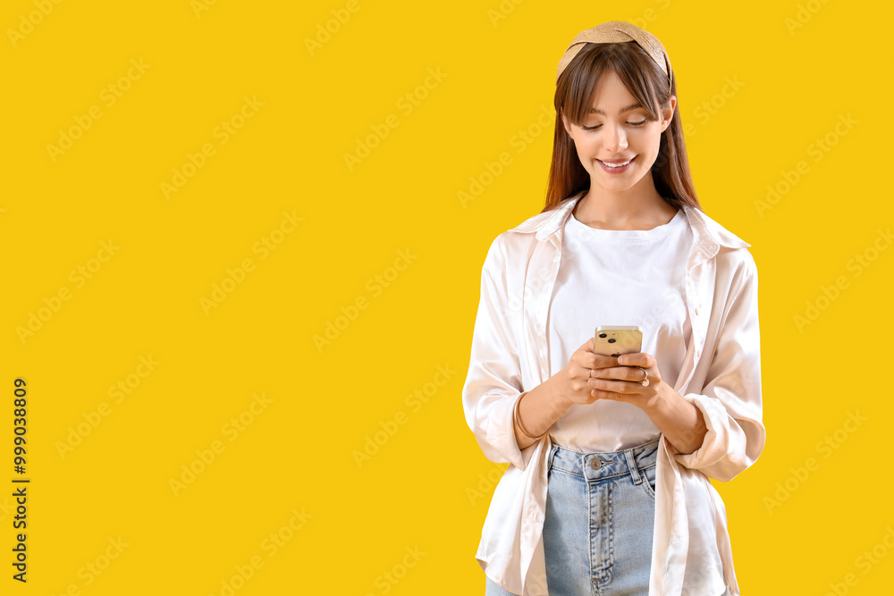 Beautiful young woman using mobile phone on yellow background Beautiful young woman using mobile phone on yellow background