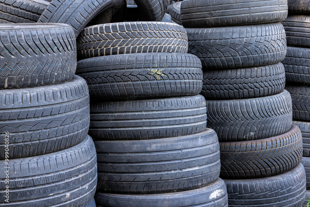 Stack of old, worn and damaged tires lying in a landfill. Decreased road safety and environmental pollution from rubber waste
