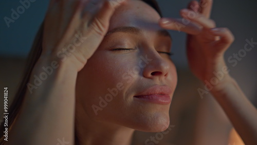 Woman making facial massage at evening apartment close up. Girl massaging face  photo