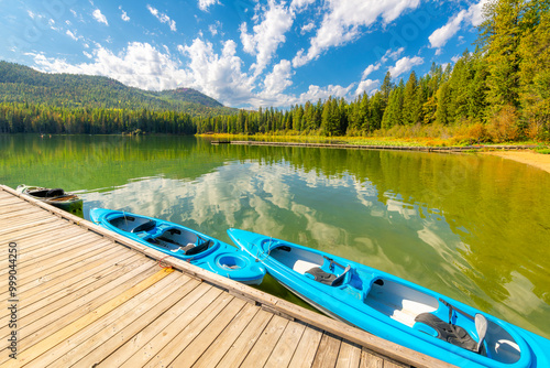 Kayaks tethered to a wooden dock along sandy beach shoreline of Cocolalla Lake, one of the many small natural lakes in the panhandle region of Coeur d'Alene, Idaho USA. photo