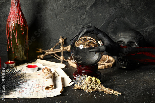 Bloody witch hand with crystal ball and magic attributes on grunge black background. Halloween celebration photo