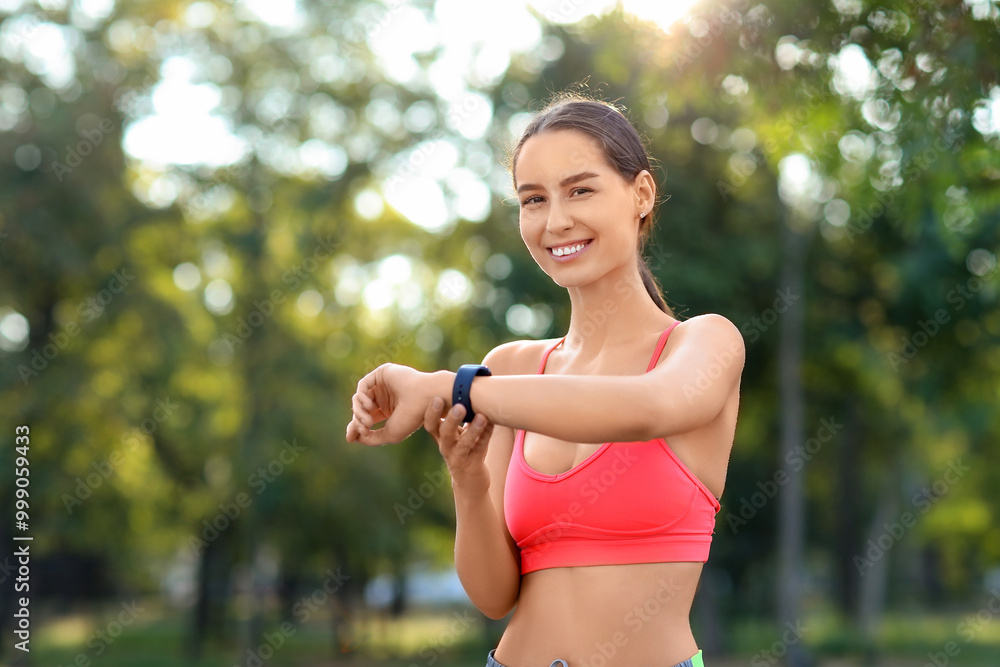 Fototapeta premium Sporty young woman with smartwatch in park