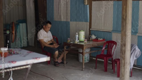 mature vietnamese man entertains himself with his smartphone in vietnam A small stall in the market of Vietnam photo