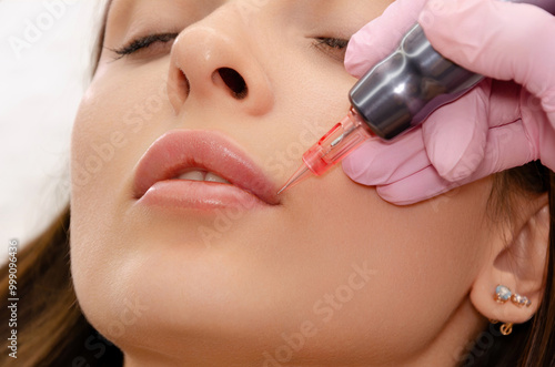 Young woman getting lip tattoo procedure in beauty salon. Permanent makeup lips.  photo