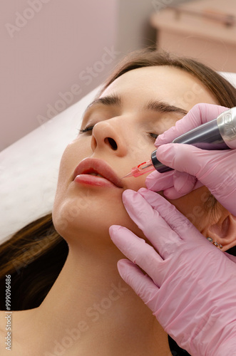 Young woman getting lip tattoo procedure in beauty salon. Permanent makeup lips.  photo