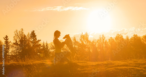 Billede på lærred CLOSE UP, LENS FLARE: Golden autumn evening sunbeams shine on happy woman bonding with loving little dog