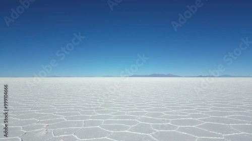 Drone shot flying low and straight over the Salar de Uyuni in Bolivia, Bolivia, the world's largest salt flat, towards the mountains on the horizon