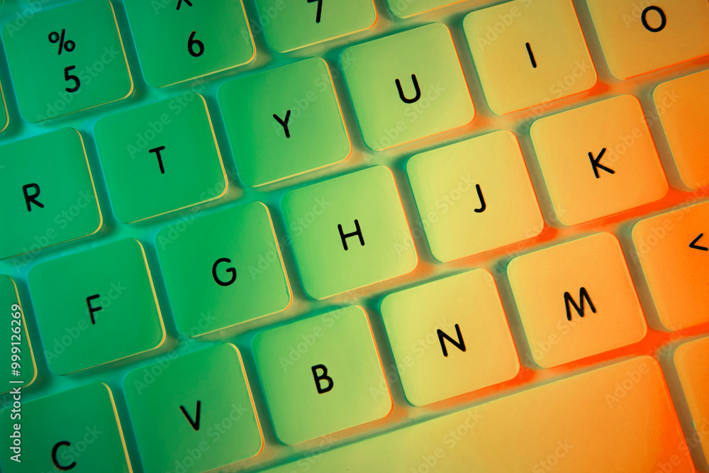 Top view of white computer keyboard illuminated with colorful lights, close-up shot Top view of white computer keyboard illuminated with colorful lights, close-up shot