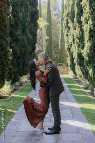 An enchanting engagement photoshoot in a romantic garden showcases a diverse couple radiating love and joy, highlighting their unique connection and deep affection, creating lasting memories