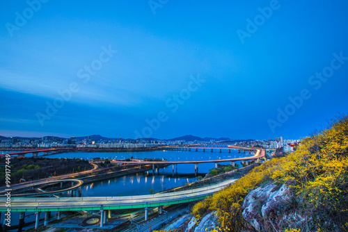 Eungbongsan Mt, Seongdong-gu, Seoul, South Korea - March 28, 2020: Aerial view of Jungnangcheon Creek with Yongbigyo Bridge and Dongbu Expressway on Han River at dawn with yellow forsythia flowers photo