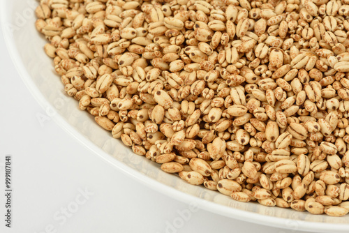 Close up of puffed barley grains in a white bowl with white background, South Korea