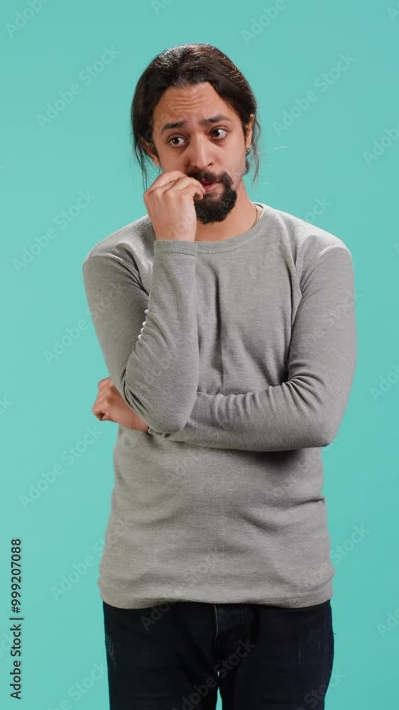 Vertical video Distraught man biting nails, being afraid of receiving troubling bad news, studio background. Anxious person suffering from mental health problems, having negative emotions, camera A Vertical video Distraught man biting nails, being afraid of receiving troubling bad news, studio background. Anxious person suffering from mental health problems, having negative emotions, camera A