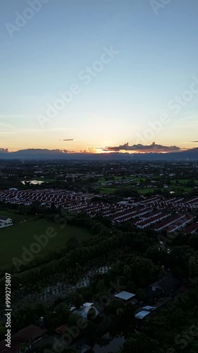 Drone timelapse, aerial view of a suburban neighborhood at sunset, showcasing a beautiful sky and distant mountains.