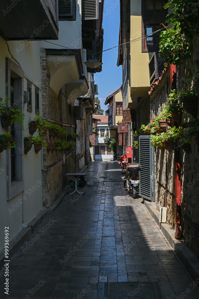 Fototapeta premium A narrow cobbled street in a resort town with flower pots along the walls