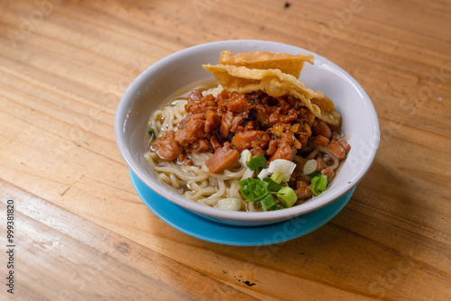 a bowl of chicken noodles, or mie ayam, on a wooden table