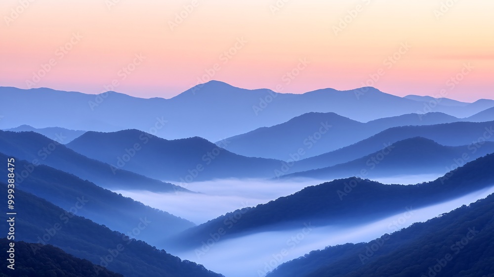 Obraz premium A panoramic view of a mountain range with mist and fog at sunrise.