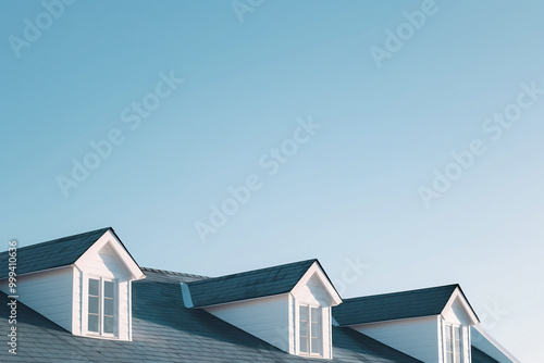 Close-up of white dormer windows on a modern house roof under clear blue sky