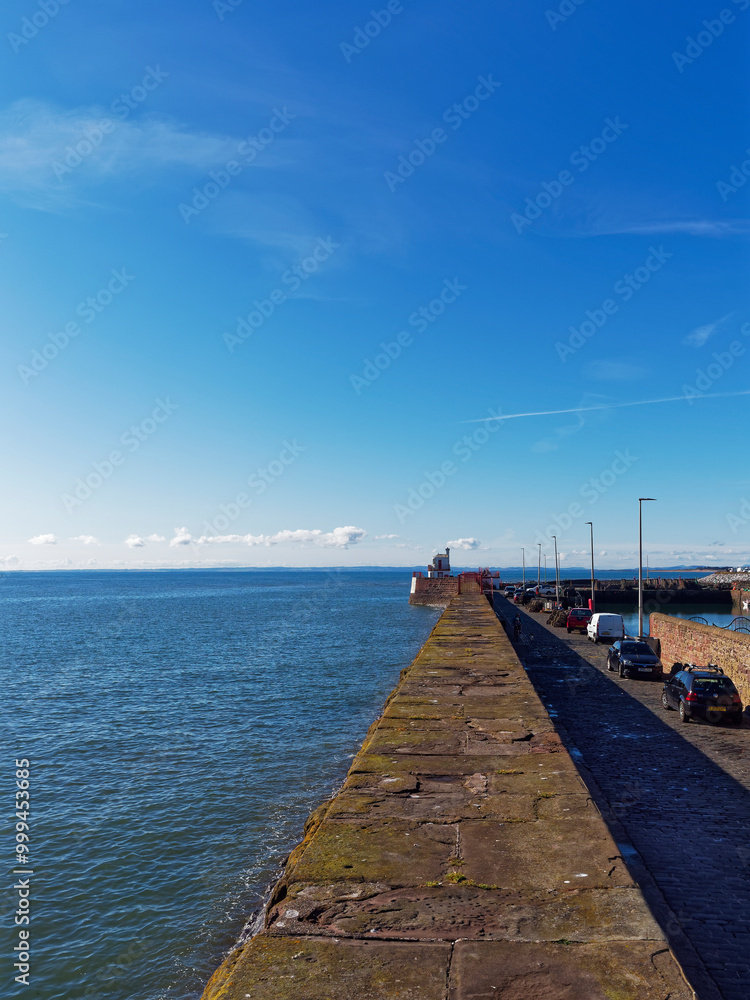 Obraz premium Looking down the traditional stone Breakwater of Arbroath East Pier towards the Harbour lighthouse and the tidal harbour area.