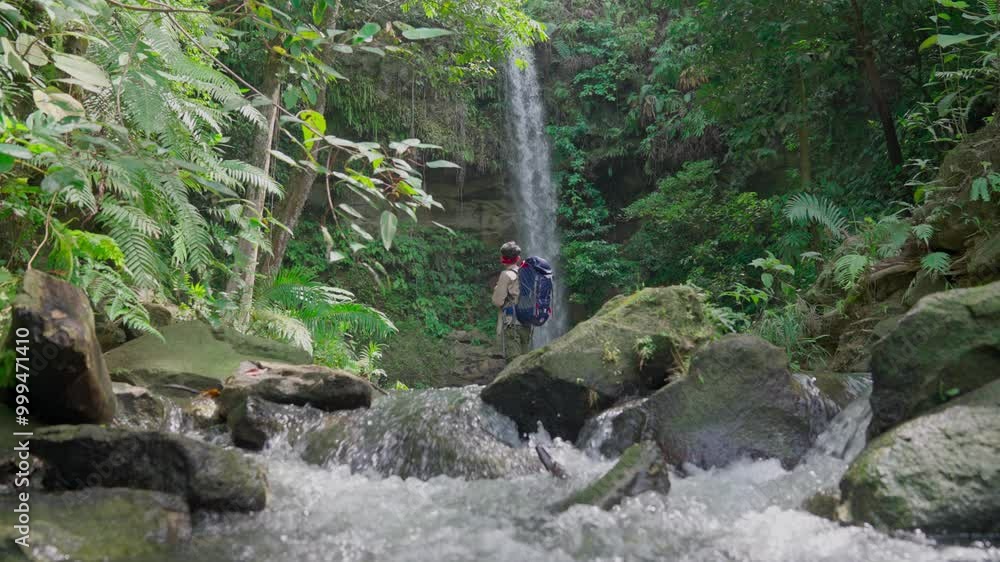 Slow motion video of a man discovering a hidden waterfall in Indonesia's tropical rainforest Slow motion video of a man discovering a hidden waterfall in Indonesia's tropical rainforest