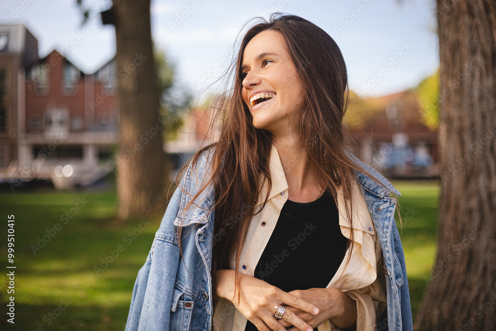 Close up portrait of beautiful confident woman laughing in nature, walk in park and look by side. Brunette woman look at side, enjoy of nature, amazement woman wear shirt, top and jeans jacket. Close up portrait of beautiful confident woman laughing in nature, walk in park and look by side. Brunette woman look at side, enjoy of nature, amazement woman wear shirt, top and jeans jacket.
