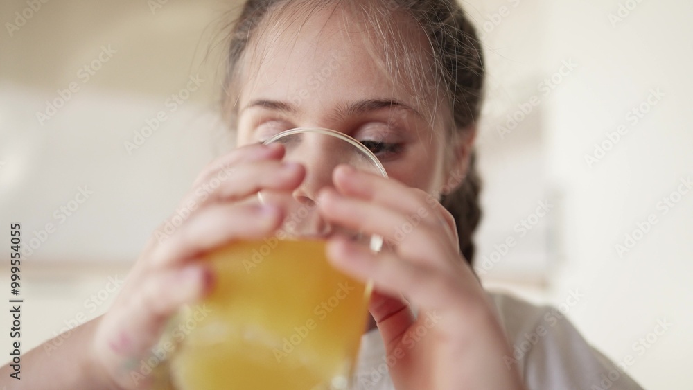 girl child drinking juice. happy family a healthy eating kid dream concept. daughter girl drinking yellow juice indoors from a glass cup in the kitchen. child drinking fruit juice girl child drinking juice. happy family a healthy eating kid dream concept. daughter girl drinking yellow juice indoors from a glass cup in the kitchen. child drinking fruit juice