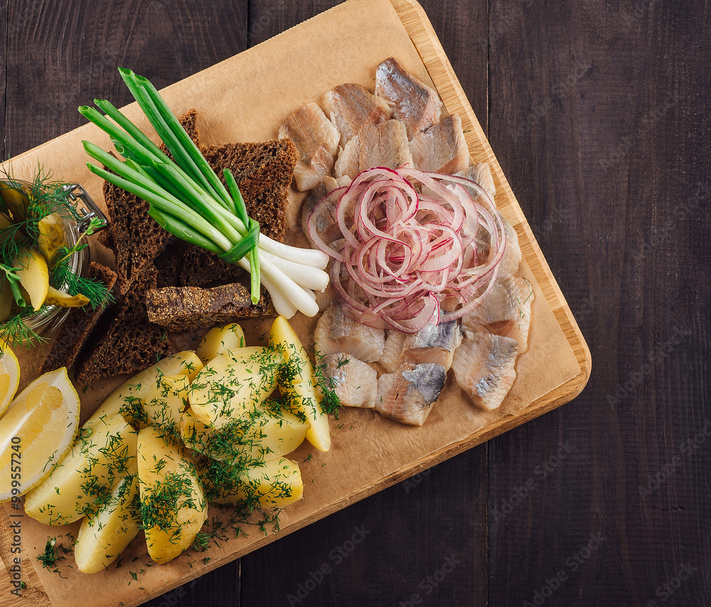 Sliced herring with potatoes and onions on wooden board Sliced herring with potatoes and onions on wooden board