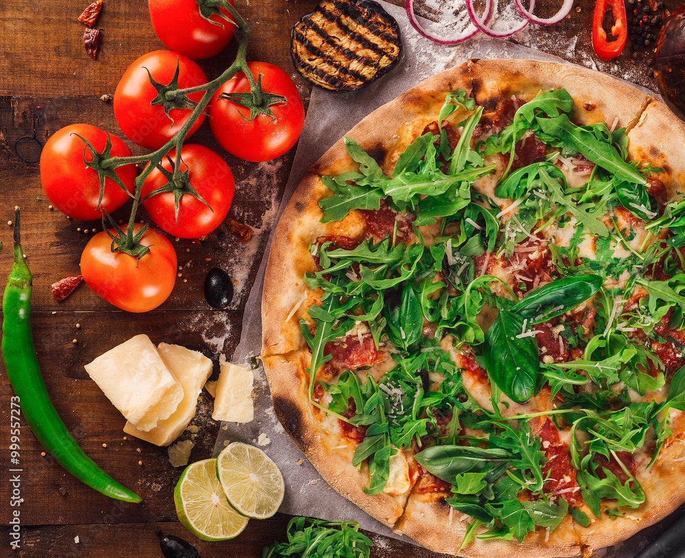 Freshly baked pizza lying on wooden table surrounded by ingredients Freshly baked pizza lying on wooden table surrounded by ingredients