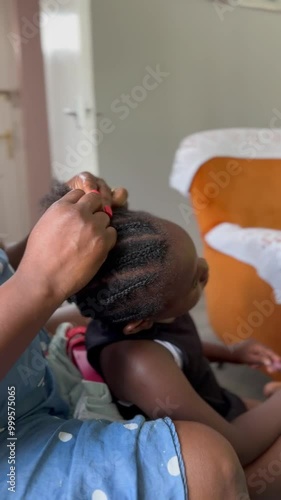 An African woman braiding her Dauther's hair 2