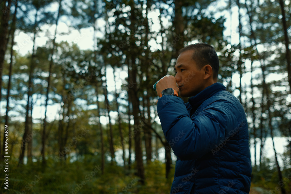 Adult asian man drink coffee in pine forest on camping trip. Royalty high-quality free best stock of man happily savoring freedom with coffee or hot tea,camper enjoying fresh air and tranquil morning Adult asian man drink coffee in pine forest on camping trip. Royalty high-quality free best stock of man happily savoring freedom with coffee or hot tea,camper enjoying fresh air and tranquil morning