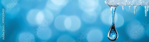 A close-up of a water droplet hanging from ice, illuminated by a soft blue background, creating a serene and refreshing atmosphere.