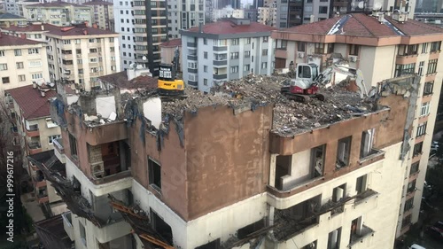 A dilapidated building in Turkish is being demolished - 4K Construction Building - Demolition digger destroying an old building - Demolition of apartment block - Medium shot of house being demolished photo