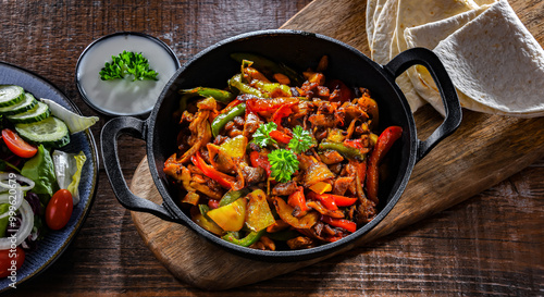 Fajita with peppers and onions served on a hot iron skillet photo