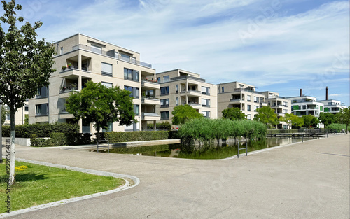 modern residential complex with multiple apartment buildings, featuring large balconies and surrounded by greenery