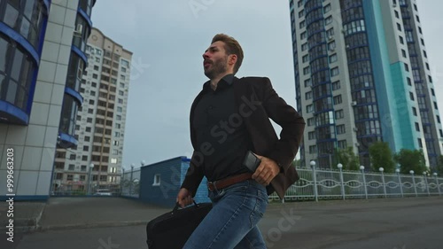 Man hurries through urban streets with briefcase on overcast day photo