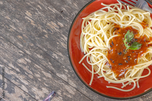 Spaghetti with Tomato Sauce. A close-up of a plate of spaghetti with tomato sauce. The spaghetti is cooked al dente and the sauce is rich and flavorful. The dish is garnished with a sprig of parsley.