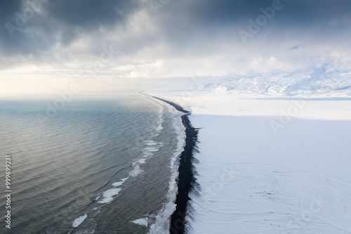 An aerial view of a black beach in Iceland. Waves and black sand on the beach. View from a drone. Winter landscape from a drone. Traveling along the Golden Ring in Iceland by car.