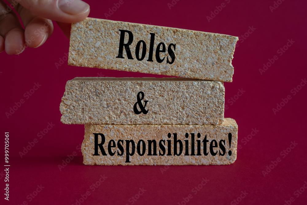 Roles and Responsibilities symbol. Concept words Roles and Responsibilities on brick blocks on a beautiful pink background. Businessman hand. Business concept.