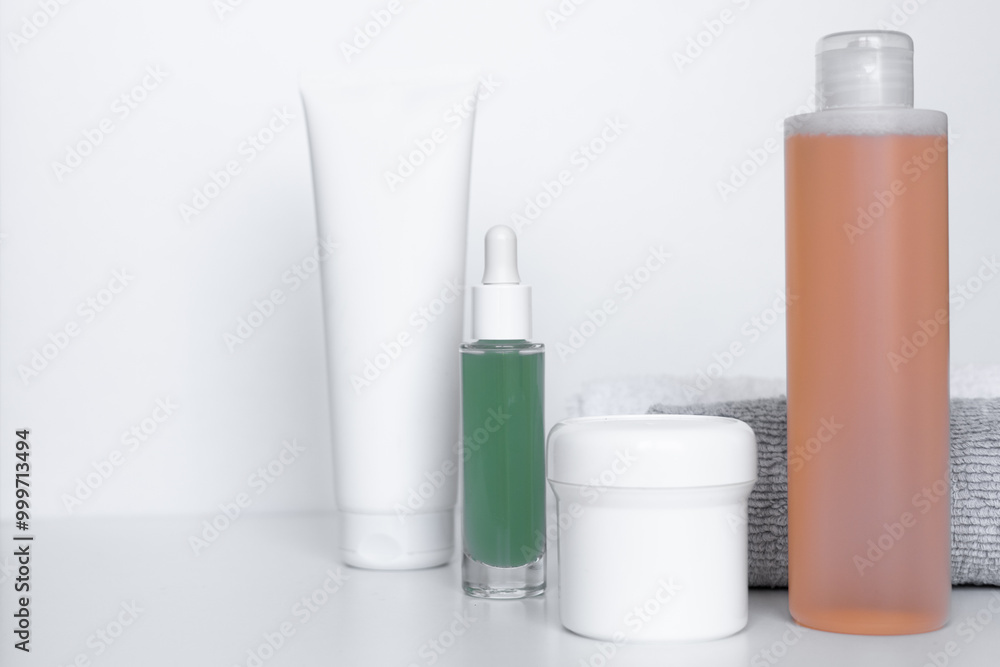 Refreshing skincare products arranged neatly on a white background with towels for self-care routine Refreshing skincare products arranged neatly on a white background with towels for self-care routine