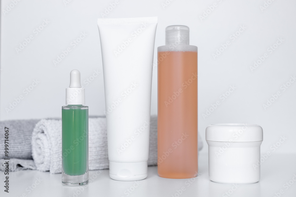 Refreshing skincare products arranged neatly on a white background with towels for self-care routine Refreshing skincare products arranged neatly on a white background with towels for self-care routine