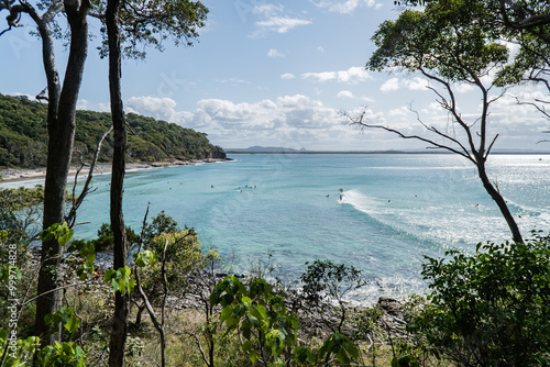 Tea Tree Bay Beach with people surfing on longboards in the national park at Noosa Heads, Queensland, Australia