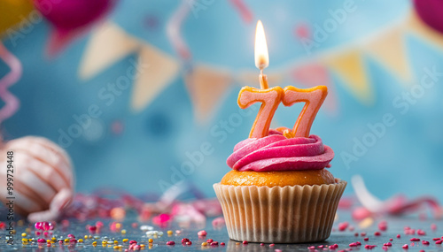 Birthday cupcake with burning lit candle with number 77. Number seventy-seven for seventy-seven years or seventy-seventh anniversary. photo