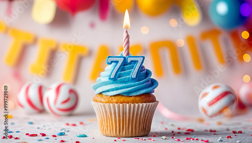 Birthday cupcake with burning lit candle with number 77. Number seventy-seven for seventy-seven years or seventy-seventh anniversary. photo