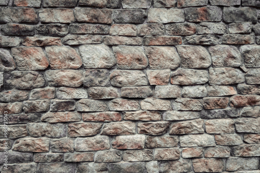 Fototapeta premium Textured stone wall with varying colors and shapes in an outdoor setting during daylight