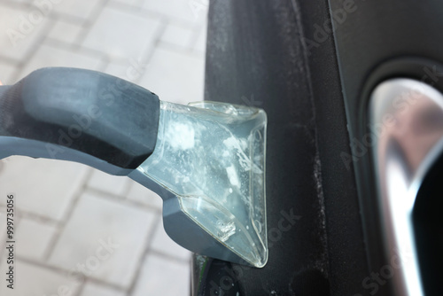 Man cleaning car door with vacuum cleaner outdoors, closeup