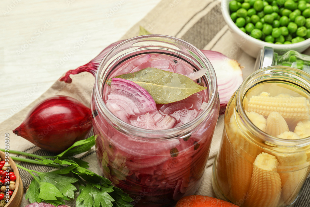 Different pickled products in jars and fresh ingredients on white table Different pickled products in jars and fresh ingredients on white table