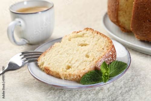 Piece of freshly baked sponge cake, mint and coffee on white textured table, closeup