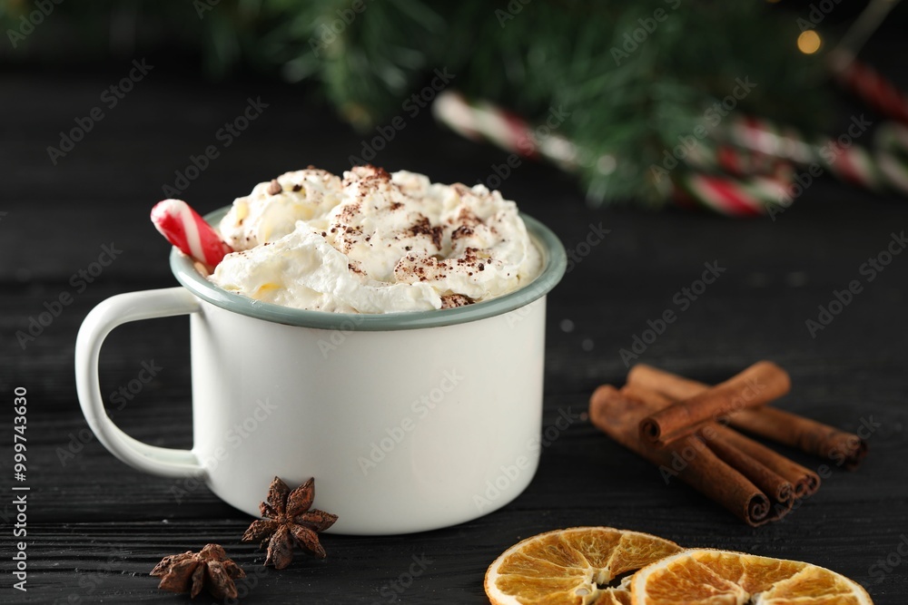 Tasty hot cocoa drink with whipped cream in mug and spices on black wooden table, closeup Tasty hot cocoa drink with whipped cream in mug and spices on black wooden table, closeup