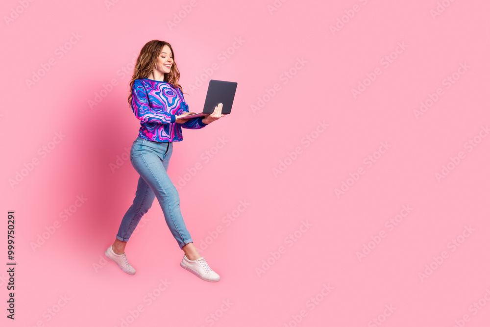 Full size photo of pretty young woman jump run empty space laptop wear pullover isolated on pink color background Full size photo of pretty young woman jump run empty space laptop wear pullover isolated on pink color background