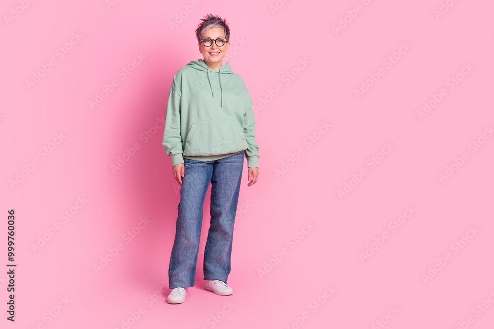 Full length photo of funny good mood lady wear khaki hoodie smiling empty space isolated pink color background Full length photo of funny good mood lady wear khaki hoodie smiling empty space isolated pink color background
