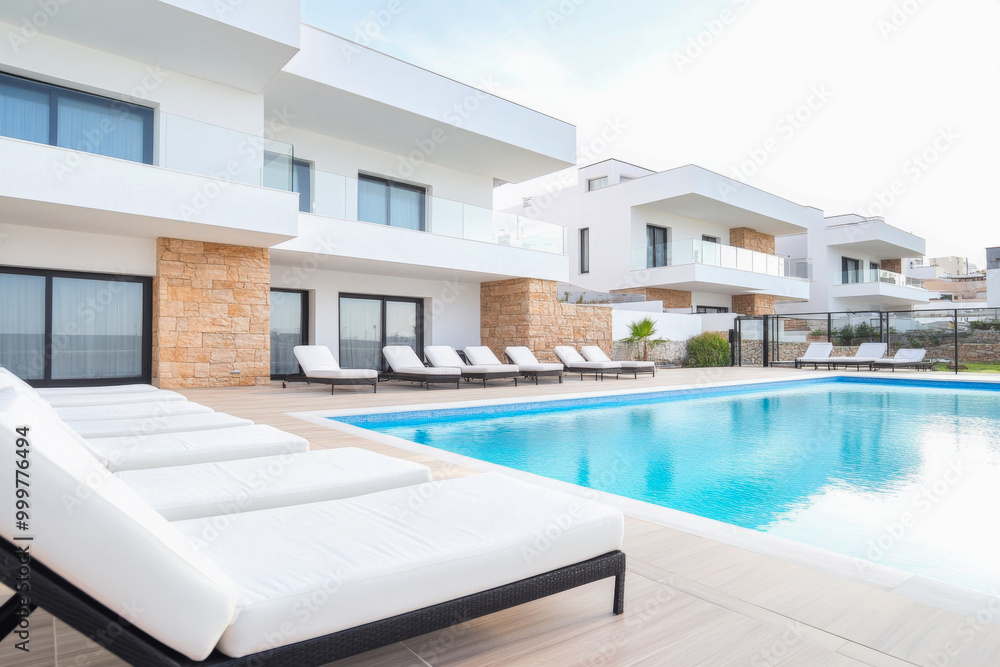 Modern residential poolside area with loungers and contemporary architecture on a sunny day Modern residential poolside area with loungers and contemporary architecture on a sunny day